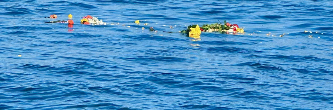 Flowers and a wreath floating on open ocean after a memorial scattering
