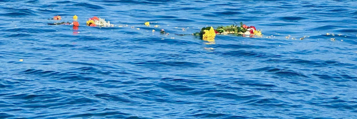Flowers and a wreath floating on open ocean after a memorial scattering